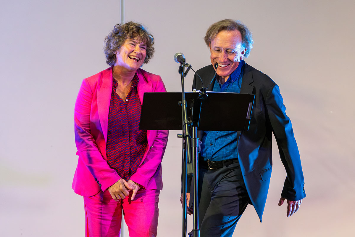 Gallery 3 - A woman and man standing at a music stand and microphone. 