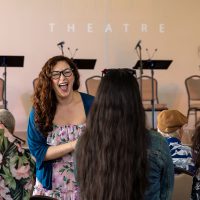 Gallery 4 - Young female playwright laughing with a group of other young women.